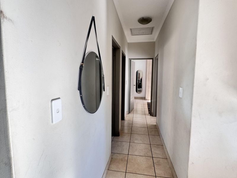 A functional hallway featuring neutral tiled flooring and access to multiple rooms, providing a clean and simple transition space within the townhouse.