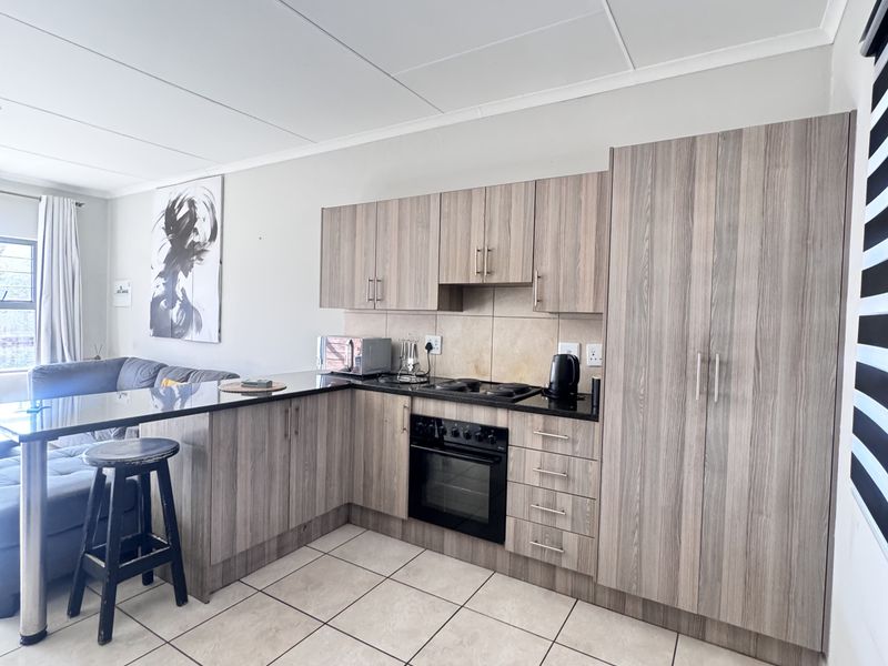 Open-plan kitchen featuring modern laminate cabinetry, built-in oven, electric hob, and a breakfast bar, seamlessly integrated with the living area.