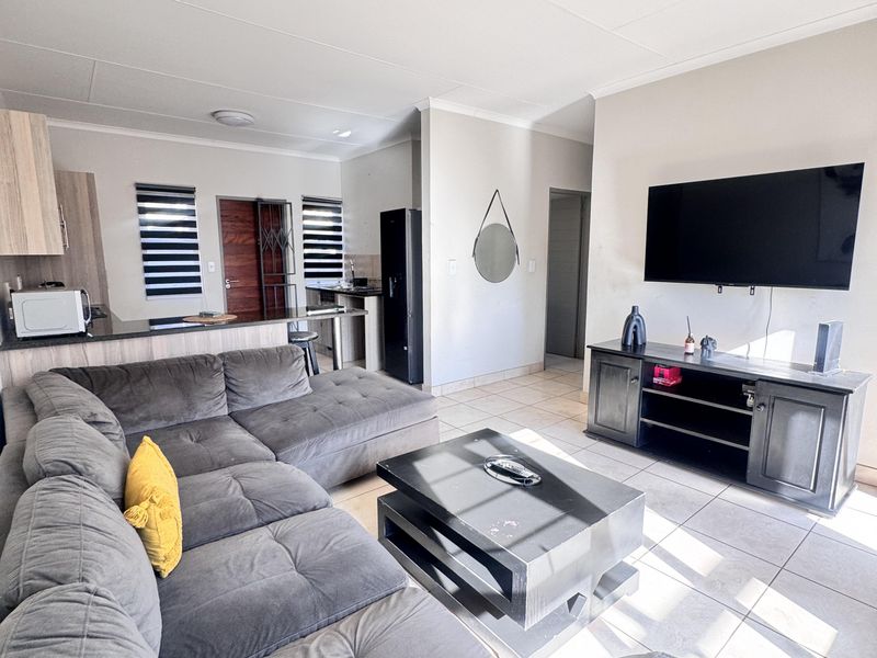An open-plan living area featuring tiled flooring, a modern kitchen with granite countertops, and a breakfast nook, creating a functional and connected living space.