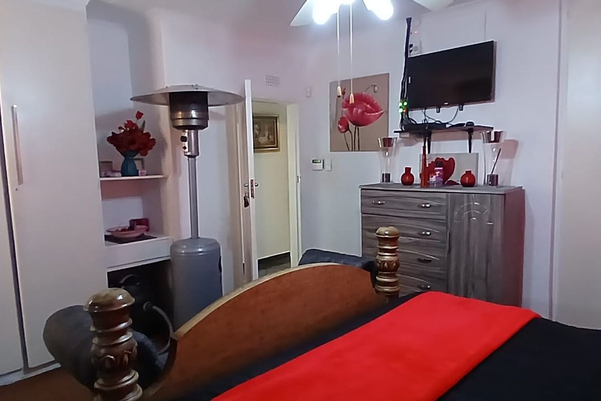 A bedroom featuring built-in cupboards, recessed shelving, and a ceiling fan, providing functional storage and climate control.