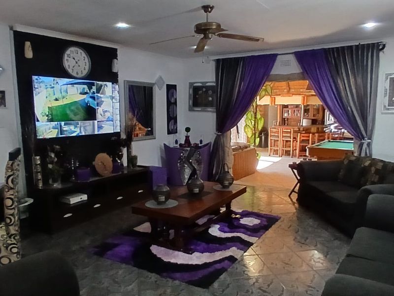 Spacious living room featuring tiled flooring, recessed lighting, and a ceiling fan, with an open transition to an adjacent entertainment area.