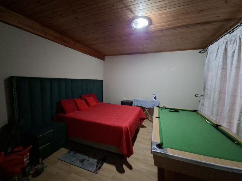 A bedroom featuring a timber ceiling and laminate flooring, currently utilized as a multi-purpose space.