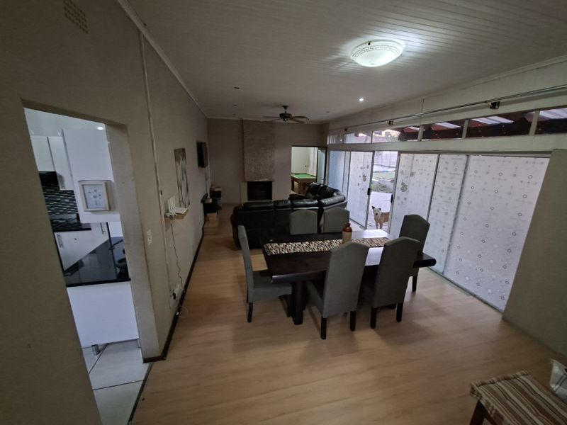 Open-plan living and dining area featuring laminate flooring, a fireplace, and large sliding glass doors providing access to the outdoor space.