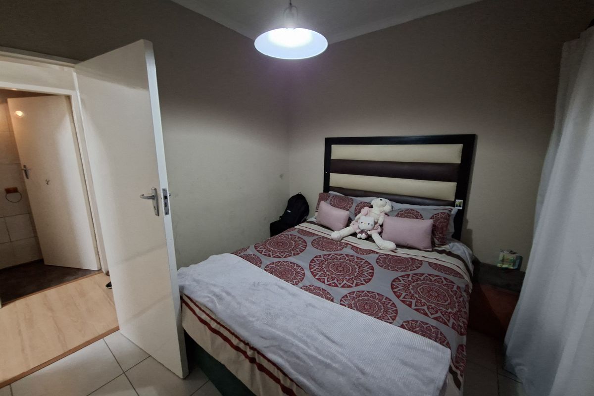 A functional bedroom featuring tiled flooring, cove cornicing, and direct access to an adjacent room.