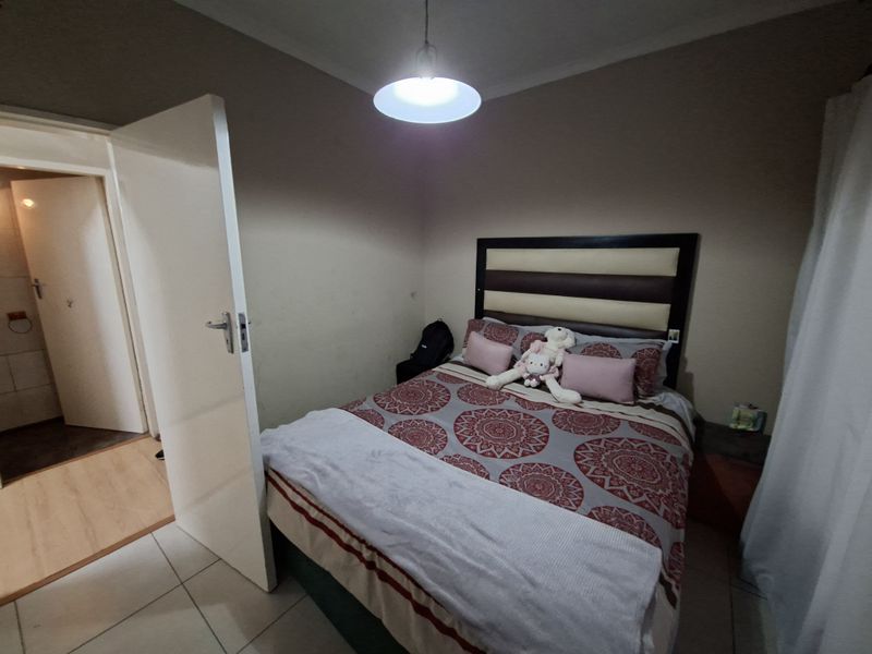 A functional bedroom featuring tiled flooring, cove cornicing, and direct access to an adjacent room.