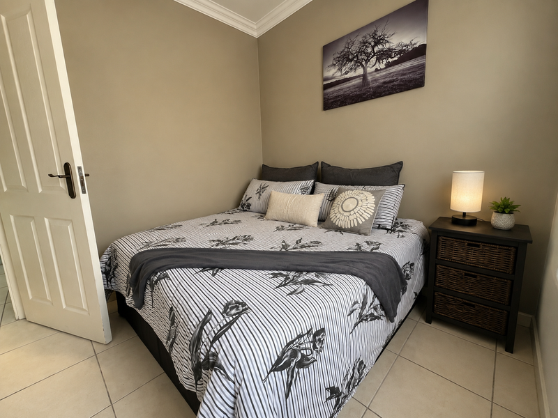 A well-maintained bedroom featuring neutral wall tones, tiled flooring, and classic coved ceiling detailing.