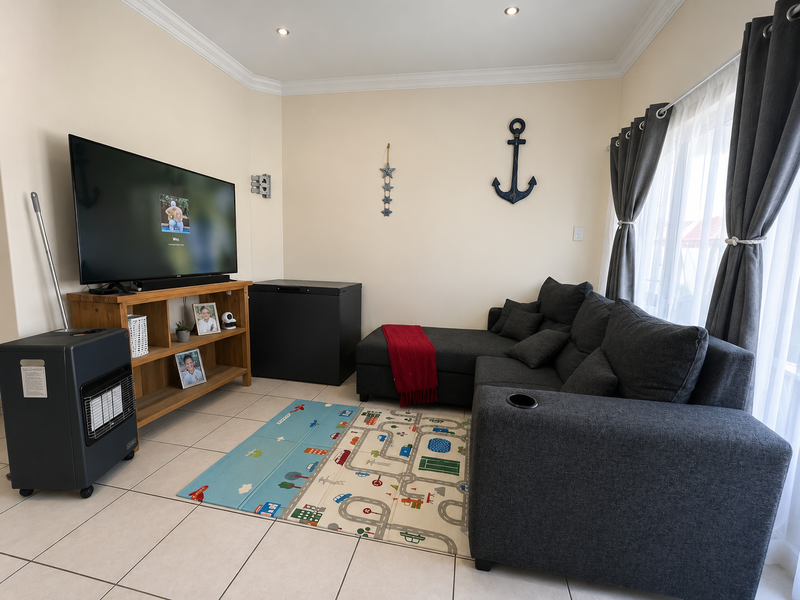 A comfortable living room featuring tiled flooring, recessed downlighting, and decorative cornicing, providing a functional and well-maintained space.