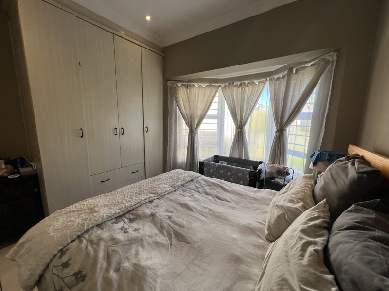 A well-lit bedroom featuring built-in cupboards and a large bay window that allows for ample natural light.