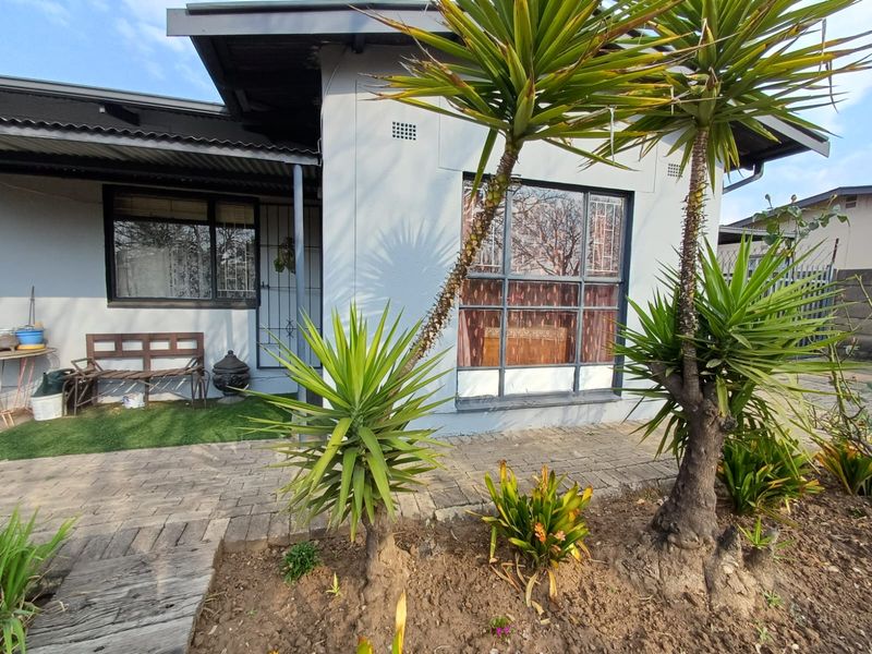 Front exterior view of the house featuring a paved walkway, covered porch area, and established garden landscaping.