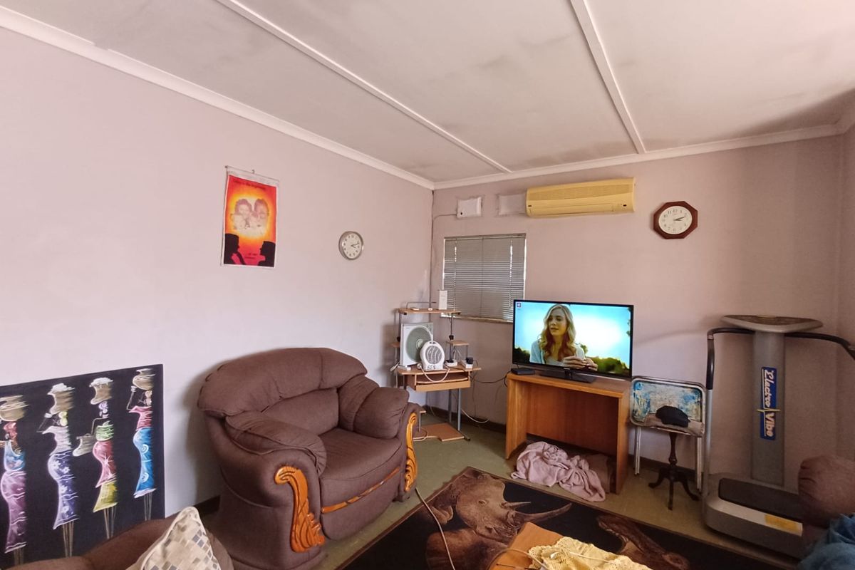 A living room featuring a split-system air conditioner and venetian blinds, offering a functional space with potential for cosmetic updates.
