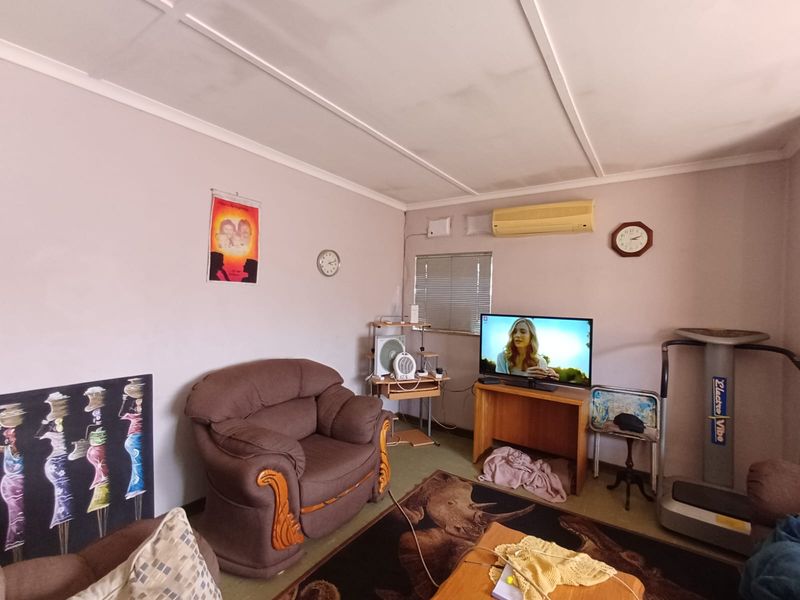 A living room featuring a split-system air conditioner and venetian blinds, offering a functional space with potential for cosmetic updates.