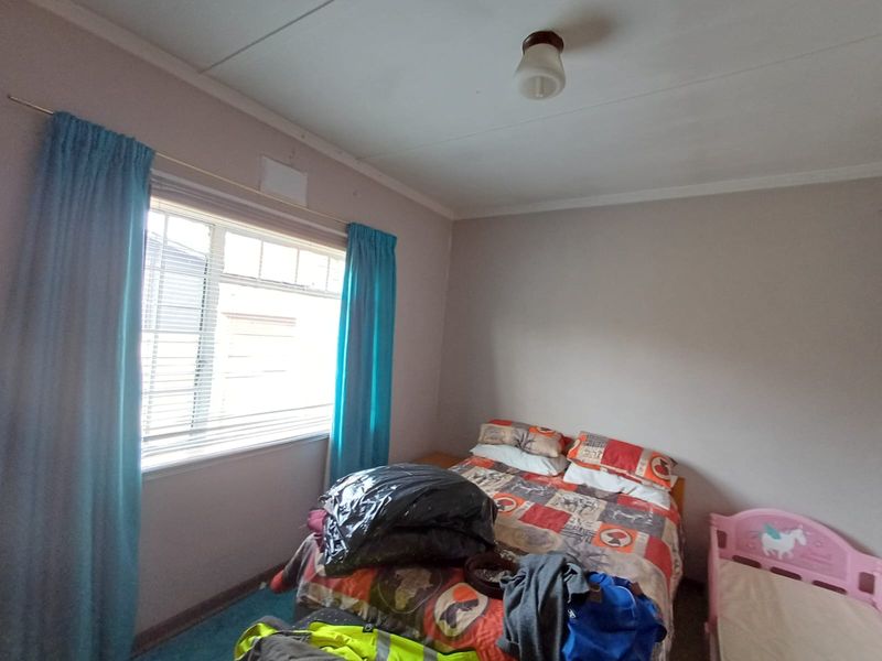 A standard bedroom featuring a window with blinds and a central ceiling light fixture.