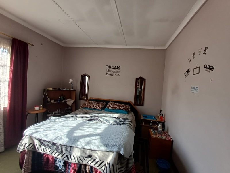 A bedroom featuring standard ceiling tiles and neutral wall paint, offering a functional space ready for cosmetic updates and personalization.