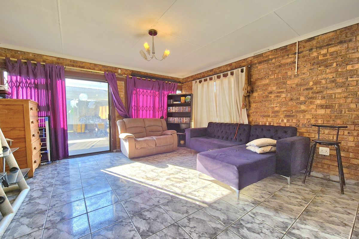 A living room featuring exposed brick walls, tiled flooring, and a sliding glass door providing access to the outdoor area.