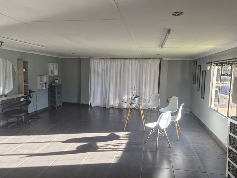 Spacious living area featuring neutral grey walls, large format floor tiles, and recessed ceiling lighting, offering a versatile open-plan layout.