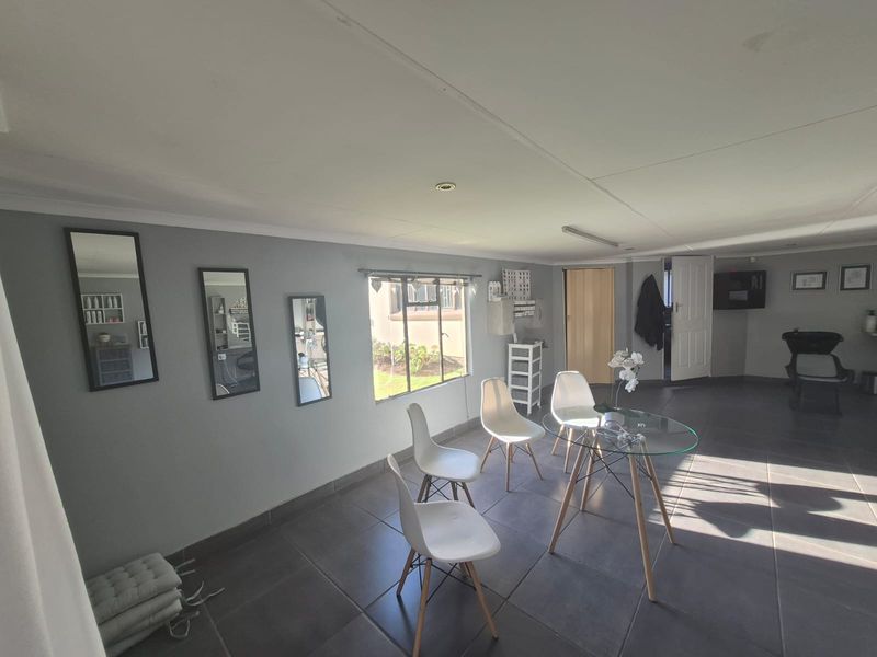 A versatile utility space featuring tiled flooring, recessed lighting, and natural light from a casement window, currently utilized as a salon area.