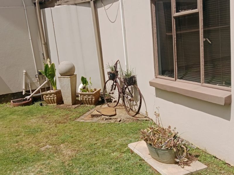 A view of the rear exterior wall and garden area featuring aluminium window frames and paved sections.