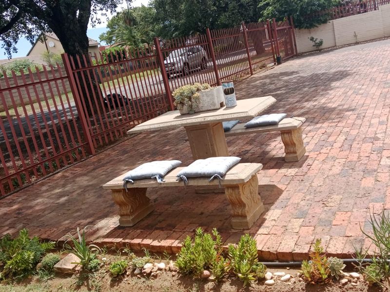 An outdoor paved patio area featuring durable brickwork and secure metal perimeter fencing, providing a functional space for outdoor seating.