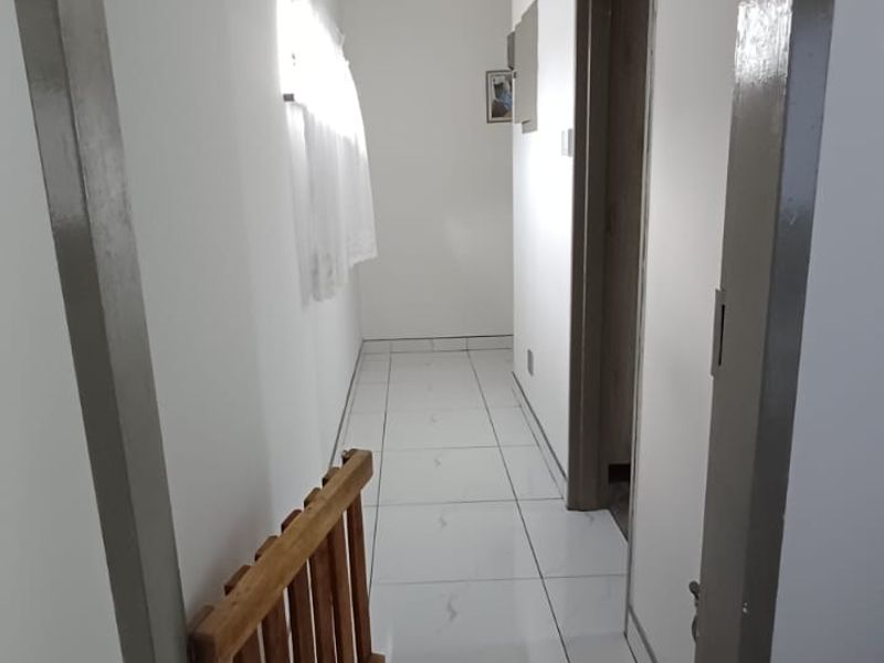 A clean, bright hallway featuring white tiled flooring and neutral wall finishes, providing a simple transition between rooms.