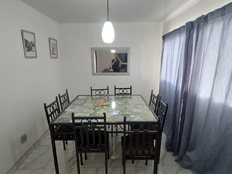 A functional dining room featuring tiled flooring, a central pendant light, and a wall-mounted mirror.