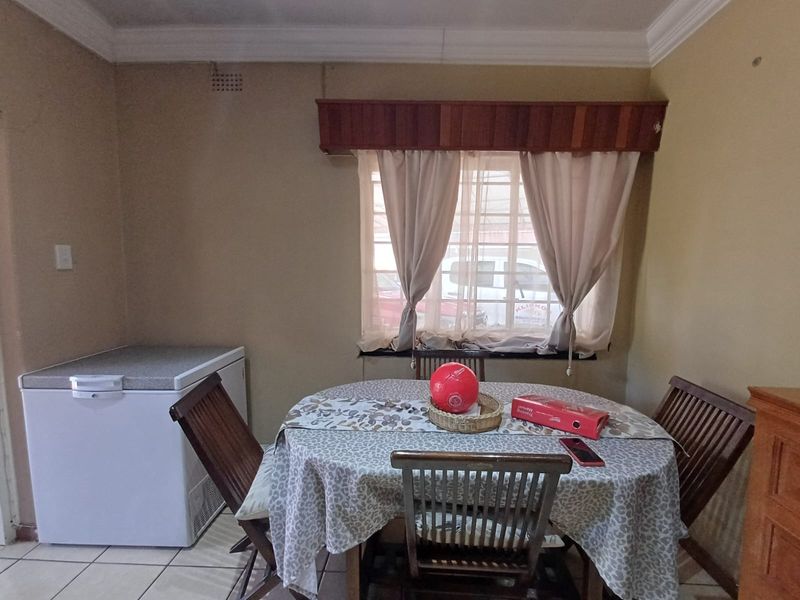 A dining area featuring tiled flooring and a window with a wooden pelmet, providing a functional space for meals.