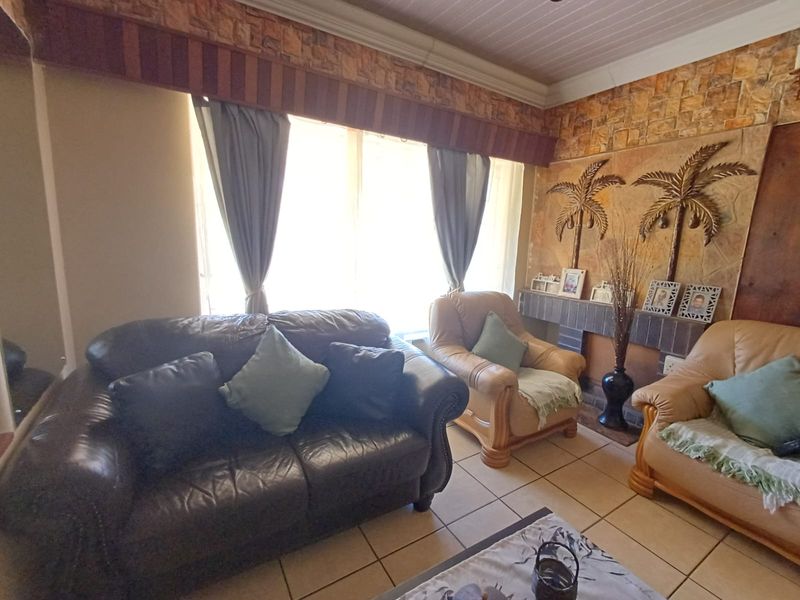 A living room featuring a stone-clad accent wall, ceramic floor tiles, and a tongue and groove ceiling with a decorative pelmet.