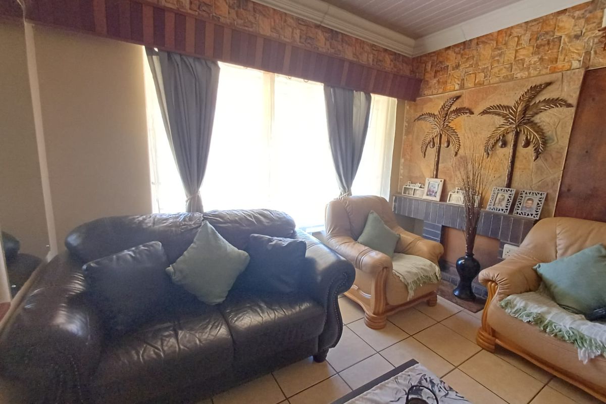 A living room featuring a stone-clad accent wall, ceramic floor tiles, and a tongue and groove ceiling with a decorative pelmet.