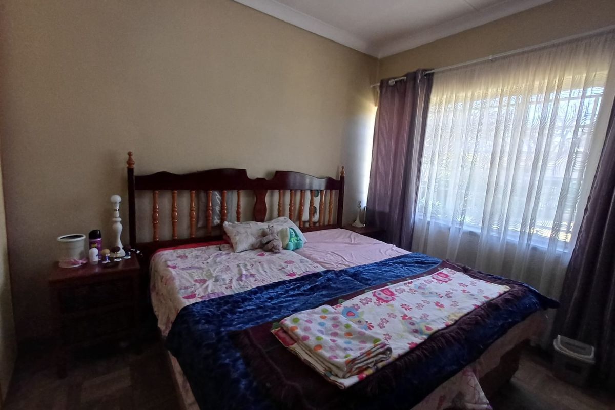 A standard bedroom featuring neutral wall tones, cove cornicing, and a window fitted with security bars for added safety.