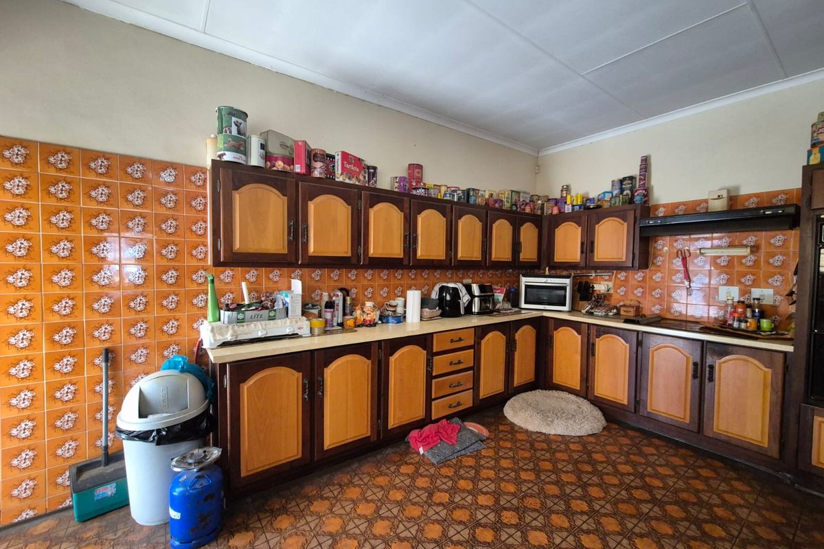 A dated kitchen featuring traditional wooden cabinetry, patterned floor tiles, and a tiled backsplash, offering significant potential for a modern renovation.