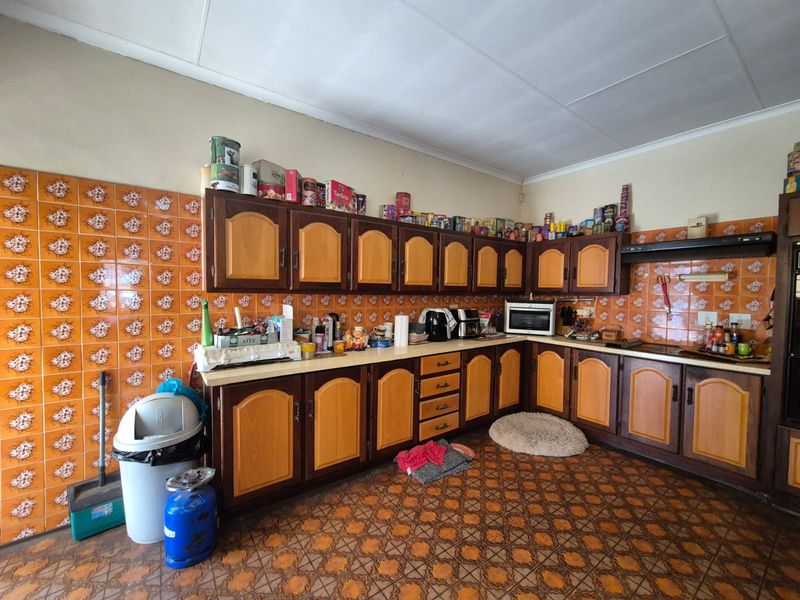A dated kitchen featuring traditional wooden cabinetry, patterned floor tiles, and a tiled backsplash, offering significant potential for a modern renovation.