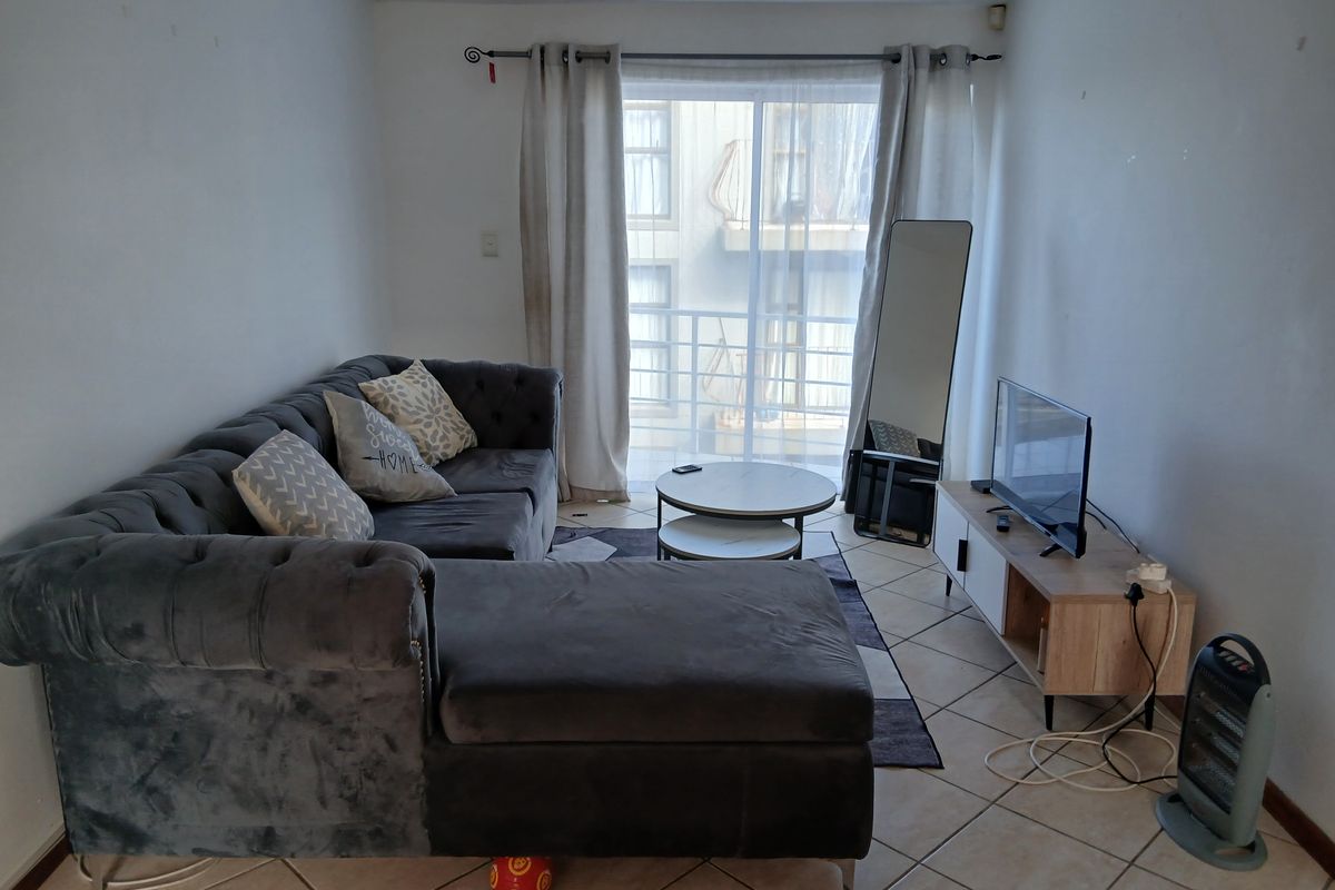 A living room featuring ceramic floor tiles and a sliding glass door leading to a balcony, providing natural light to the space.