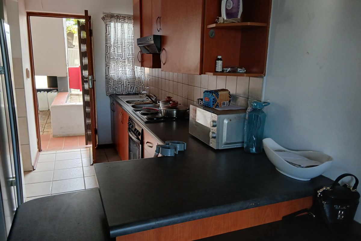 A functional kitchen featuring laminate cabinetry, built-in oven, hob, and extractor fan, with direct access to an outdoor patio area.