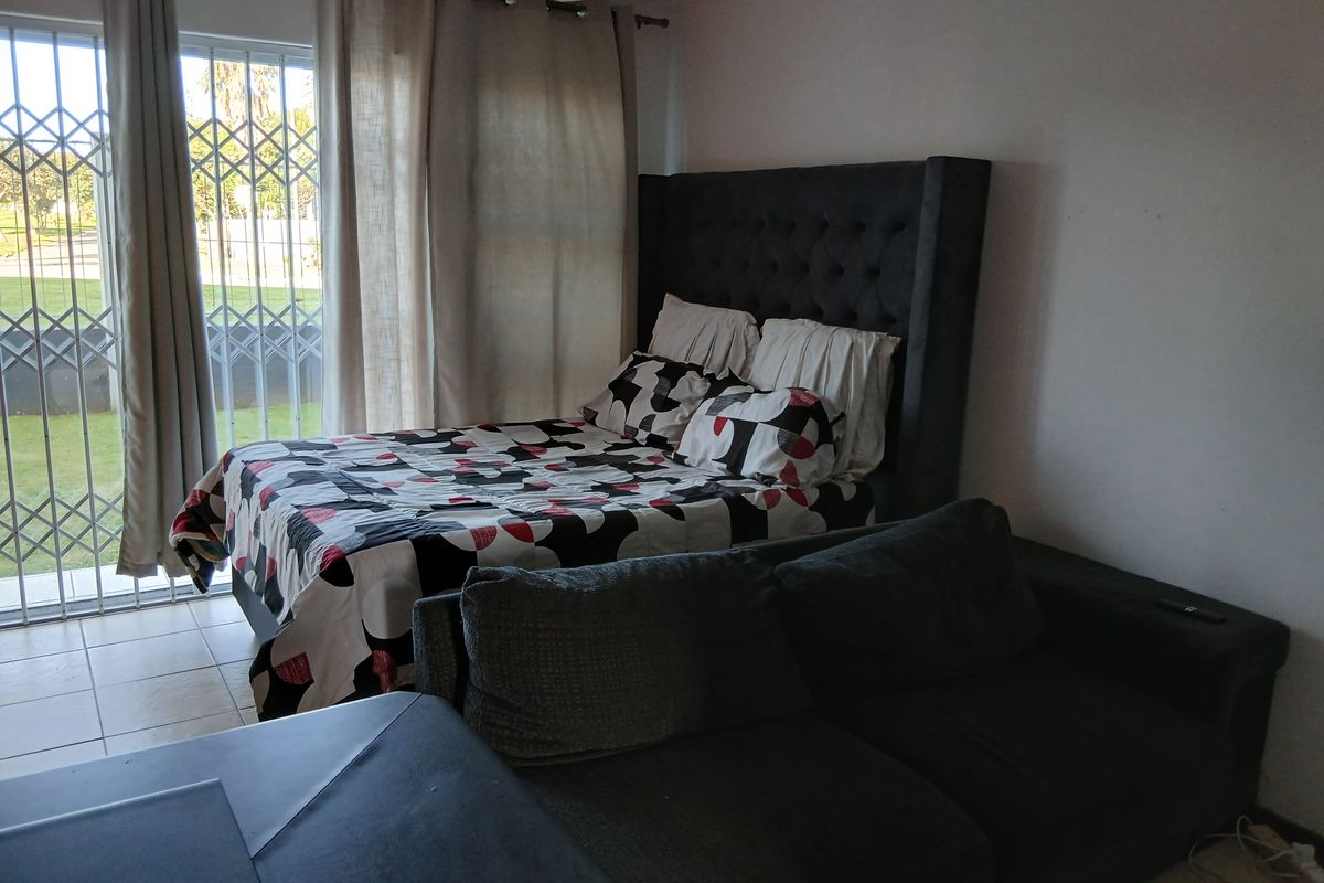 A bedroom featuring tiled flooring and a sliding glass door with a security gate, providing direct access to the outdoor area.