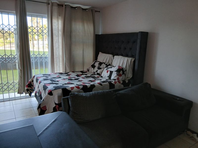 A bedroom featuring tiled flooring and a sliding glass door with a security gate, providing direct access to the outdoor area.