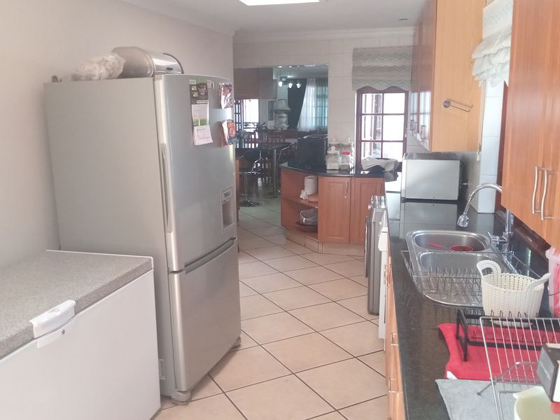 A functional kitchen featuring laminate cabinetry, granite countertops, and a double bowl stainless steel sink with tiled flooring.
