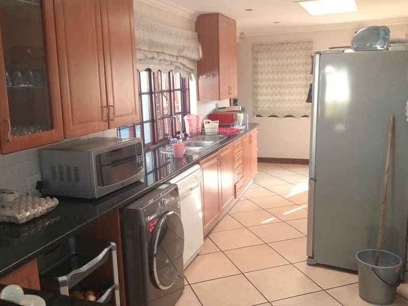 A functional kitchen featuring wooden cabinetry, granite countertops, tiled flooring, and integrated appliance spaces, offering a practical layout for daily use.