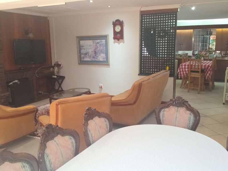 Open plan living and dining area featuring tiled flooring, a fireplace with built-in shelving, and a decorative room divider leading to the kitchen.