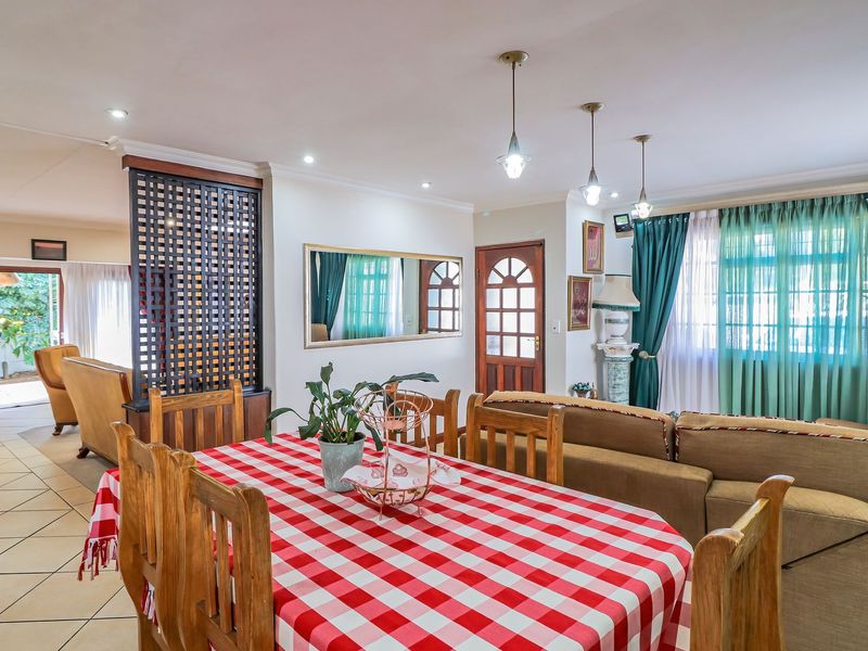 Spacious open-plan living and dining area featuring tiled flooring, decorative timber room divider, and integrated lighting, providing a versatile layout for family living.