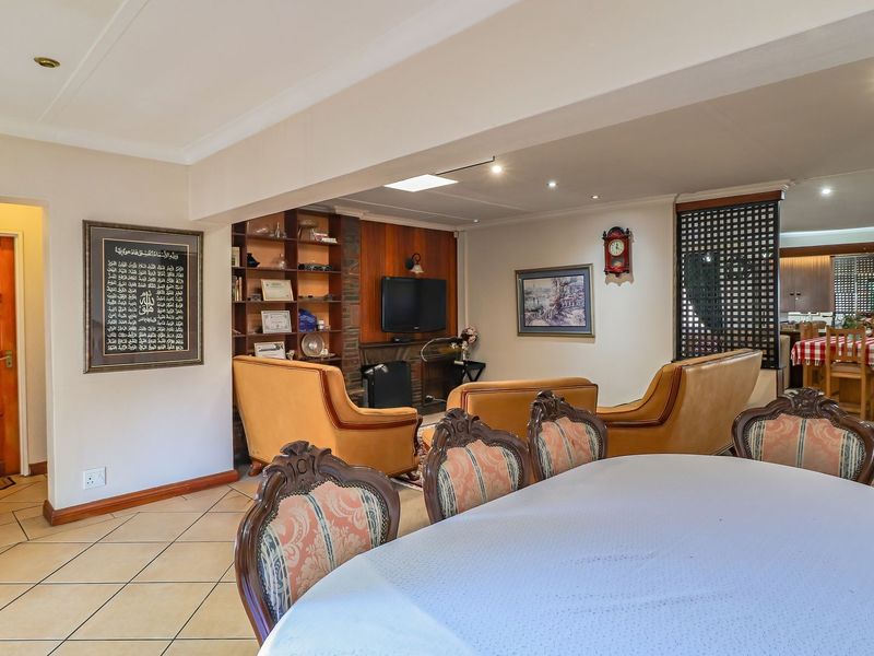 Spacious open-plan living and dining area featuring tiled floors, built-in shelving, and recessed lighting, creating a functional and connected family space.