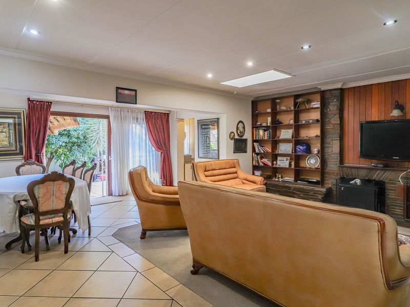 Spacious open-plan living and dining area featuring a stone fireplace, built-in shelving, wood paneling, and direct access to the outdoor patio through sliding doors.