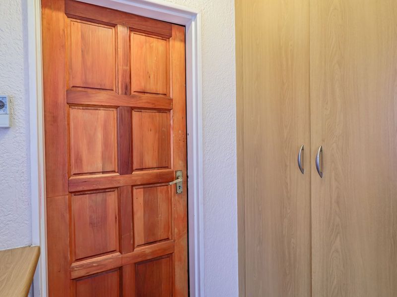A functional hallway area featuring a solid timber door and a built-in wooden cupboard for storage.