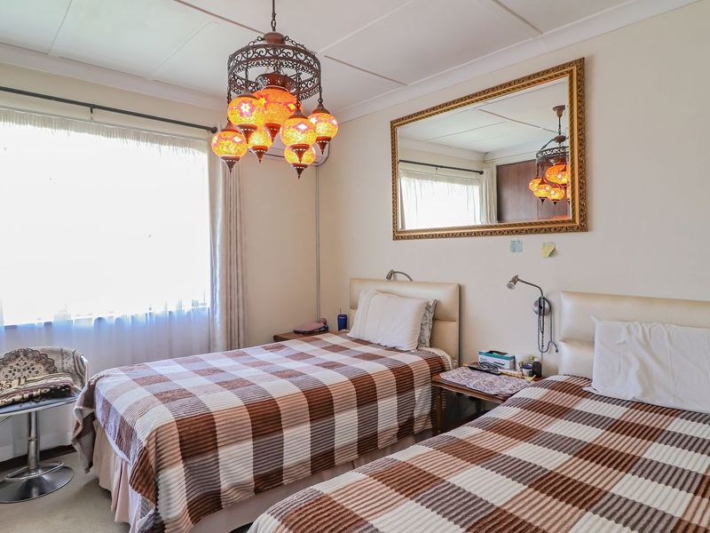 A functional bedroom featuring a tiled ceiling, wall-mounted reading lights, and large windows with curtain rails.