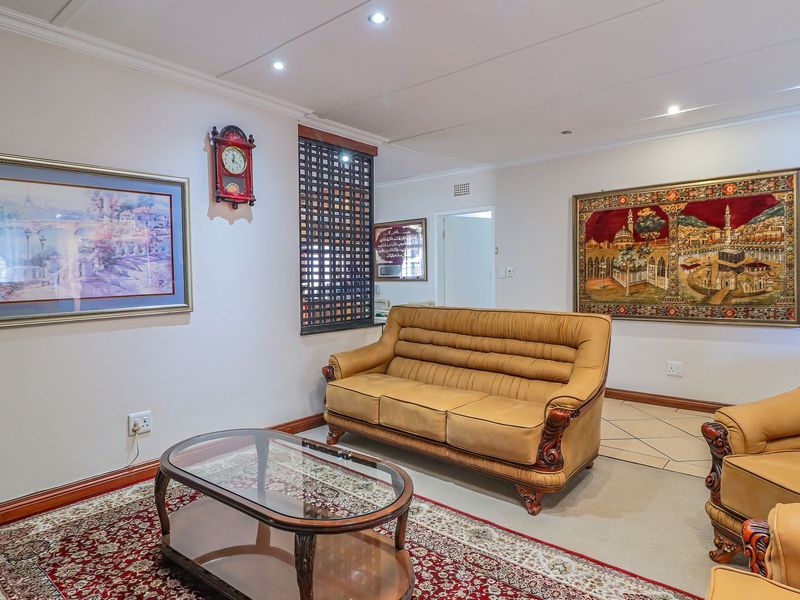 A comfortable living room featuring a mix of tiled and carpeted flooring, recessed ceiling lighting, and decorative cornice detailing.