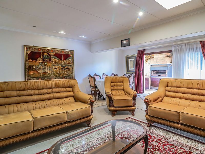 Spacious open-plan living area featuring recessed lighting, coving, and direct access to an outdoor patio with a built-in braai.