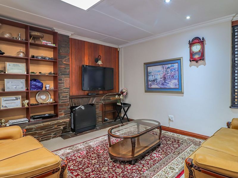 A cozy living room featuring a stone fireplace, built-in wooden shelving, and a skylight, providing a warm and traditional atmosphere.