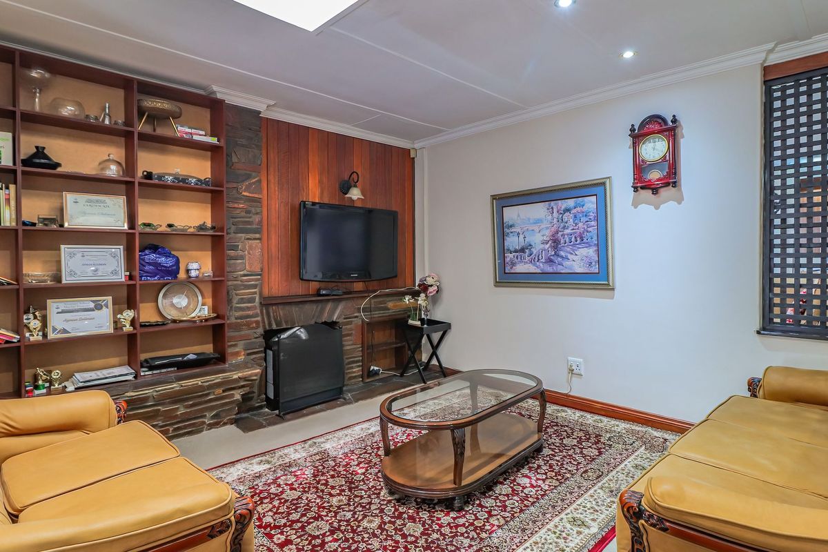 A cozy living room featuring a stone fireplace, built-in wooden shelving, and a skylight, providing a warm and traditional atmosphere.