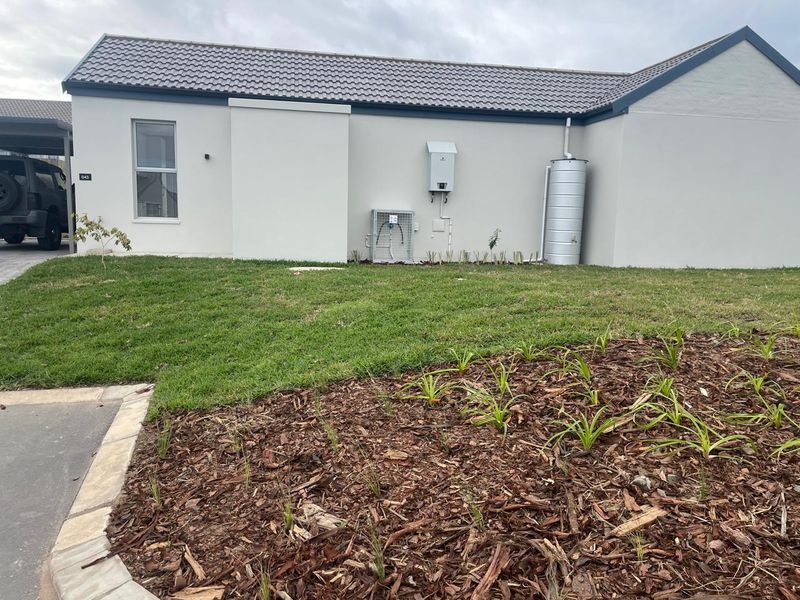 Front exterior view of the house featuring a tiled roof, landscaped garden with mulched beds, and installed utility services including a gas geyser and water tank.
