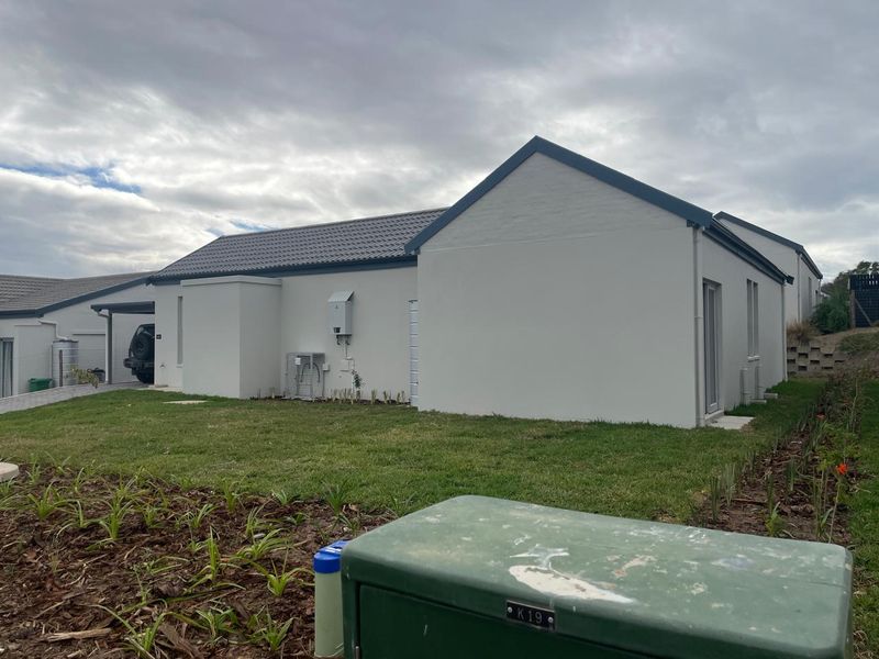 Rear view of a modern residential property featuring a tiled roof, plastered exterior walls, and a well-maintained garden area.