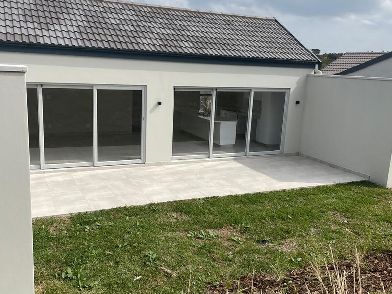 Rear view of the property featuring a tiled patio, sliding glass doors leading to the interior, and a private garden area.
