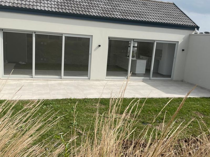 Rear view of the property featuring a paved patio area, large sliding glass doors, and a modern tiled roof.